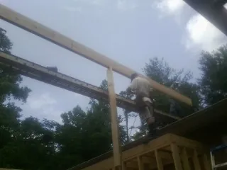 Carpenter setting a ridge beam over a new addition frame — Ice Dam Removal by Roofing Brothers in Keuka Park