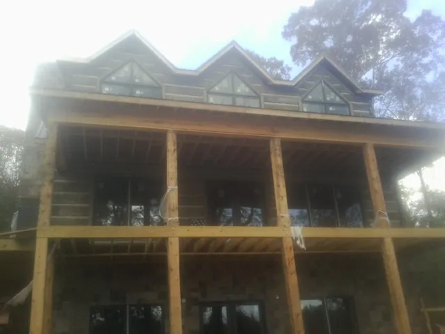Dormers and porch framing on a large log home under construction — Roof Coating work by our crew in Keuka Park