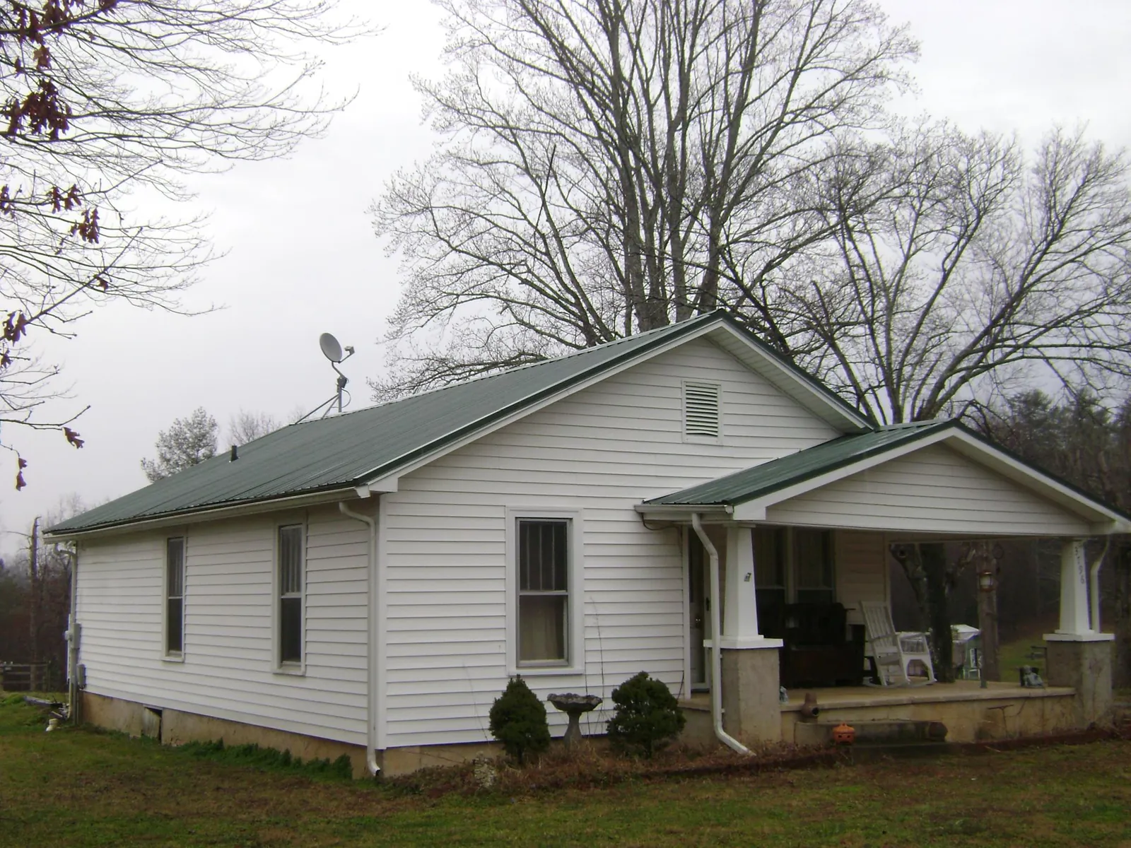 Green metal roof on a white bungalow with a side porch in Keuka Park