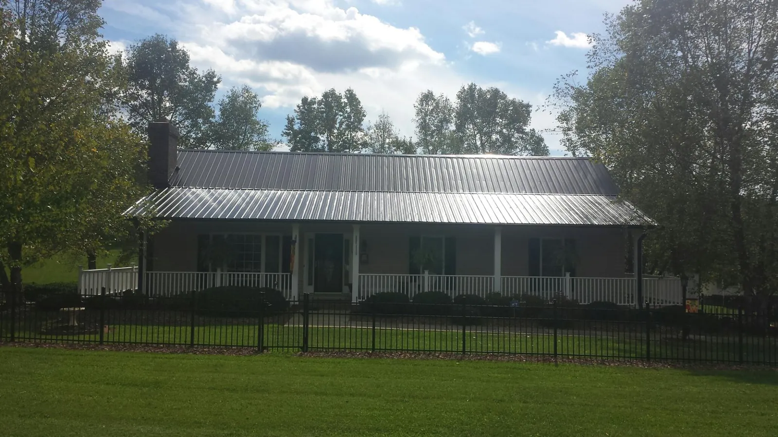 Gray metal roof on a brick ranch with a full width front porch — Gutter Guard Installation work by our crew in Keuka Park