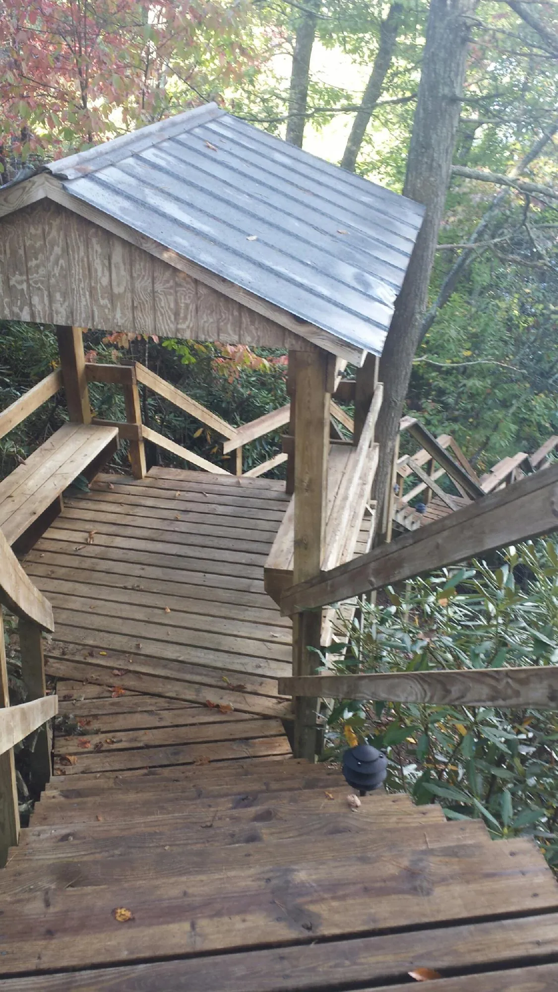 Metal roofed shelter over wooden steps on a wooded walkway — Skylight Repair & Installation work by our crew in Keuka Park