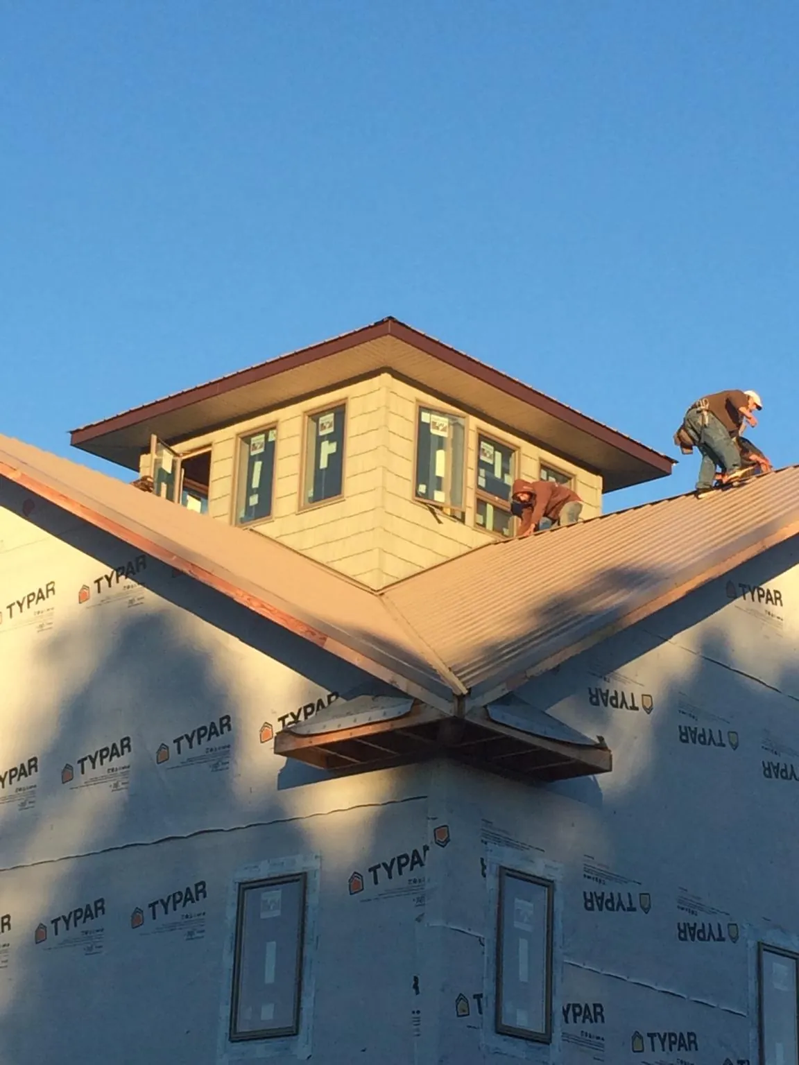 Roofers working around a rooftop cupola on a new metal roof at sunset — Roof Waterproofing in Keuka Park by Roofing Brothers